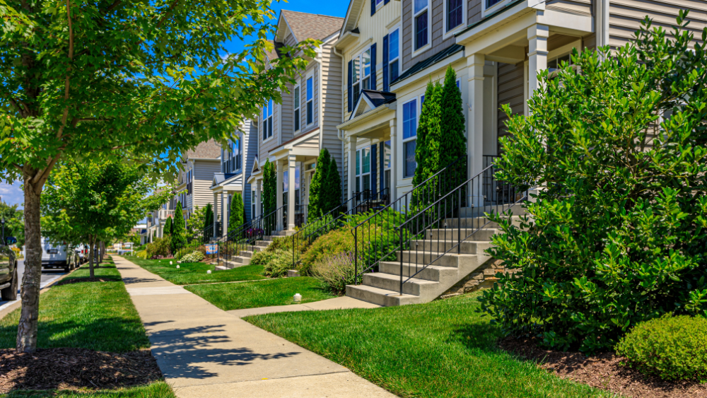 Side angle curbside view of row homes at Brunswick Crossing with landscaped yards and walking path